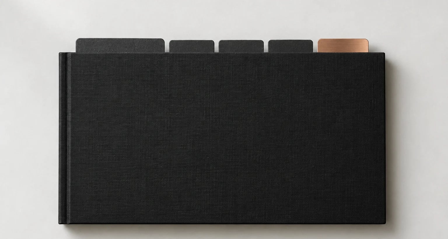 A black linen working file seen from above, with five dividers: one wide, three narrow and one in copper