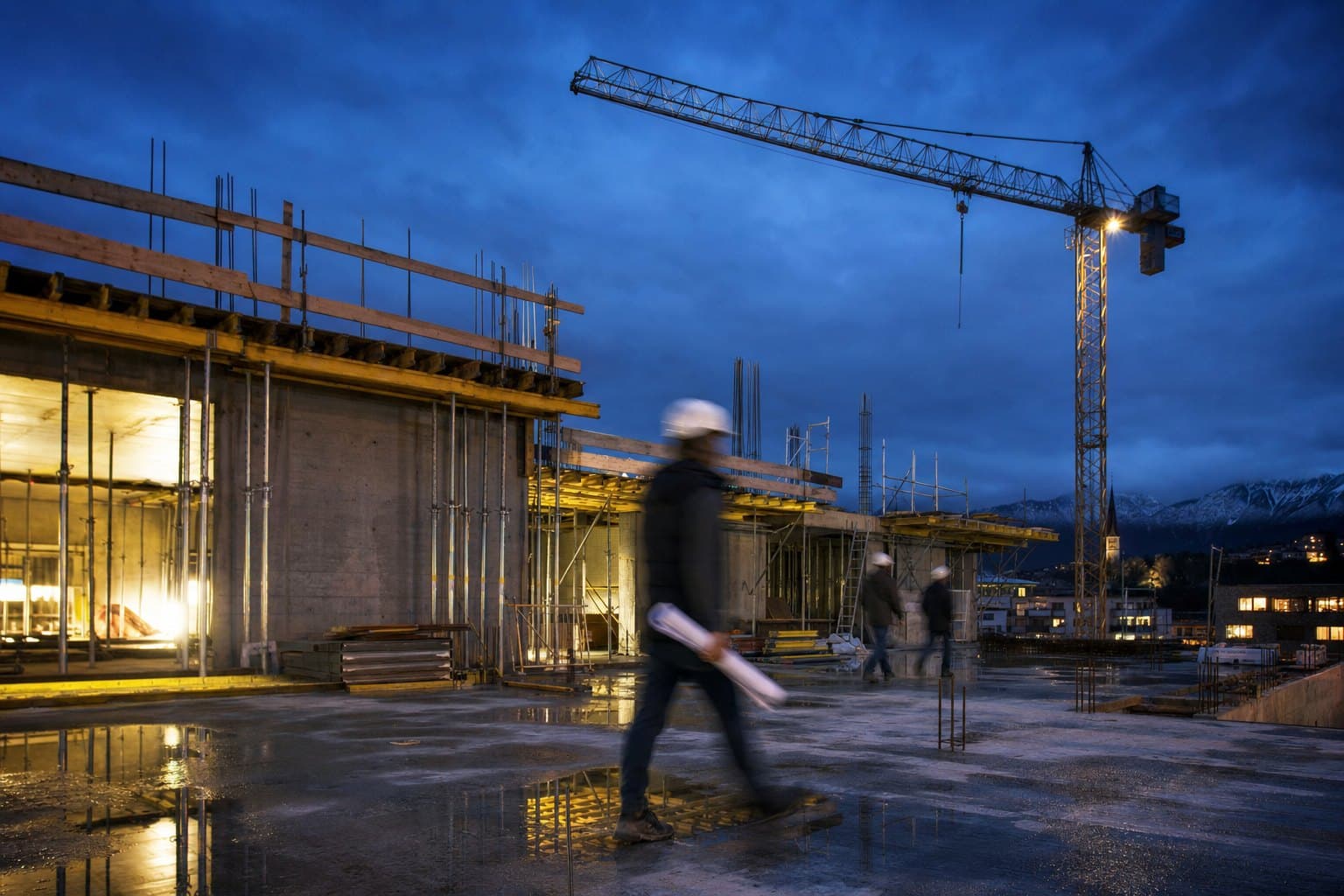 Chantier d’une promotion au crépuscule, dalle et coffrages nets, grue à l’arrêt, chef de chantier flou avec ses plans : en attendant le seuil de prévente
